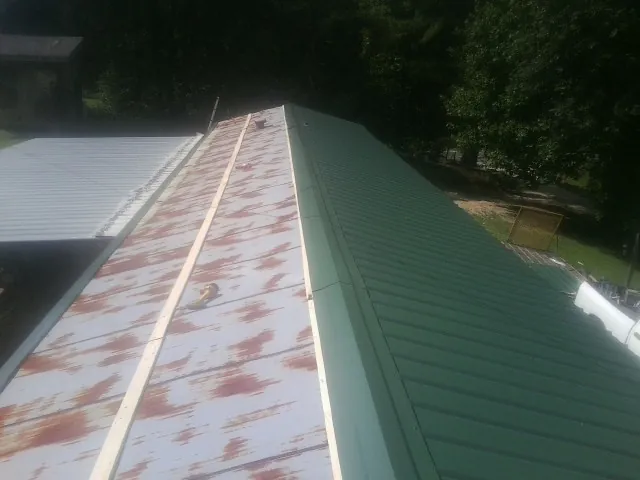 Old rusted panels beside newly installed green metal roofing — Wind Damage Roof Repair by Roofing Brothers in Staplehurst