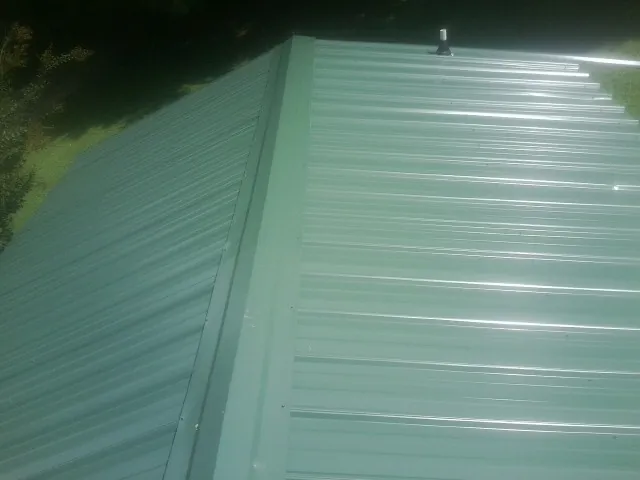 New green metal panels meeting at the ridge of a roof — Flat Roof Repair work by our crew in Staplehurst