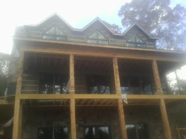 Dormers and porch framing on a large log home under construction — Roof Coating work by our crew in Staplehurst