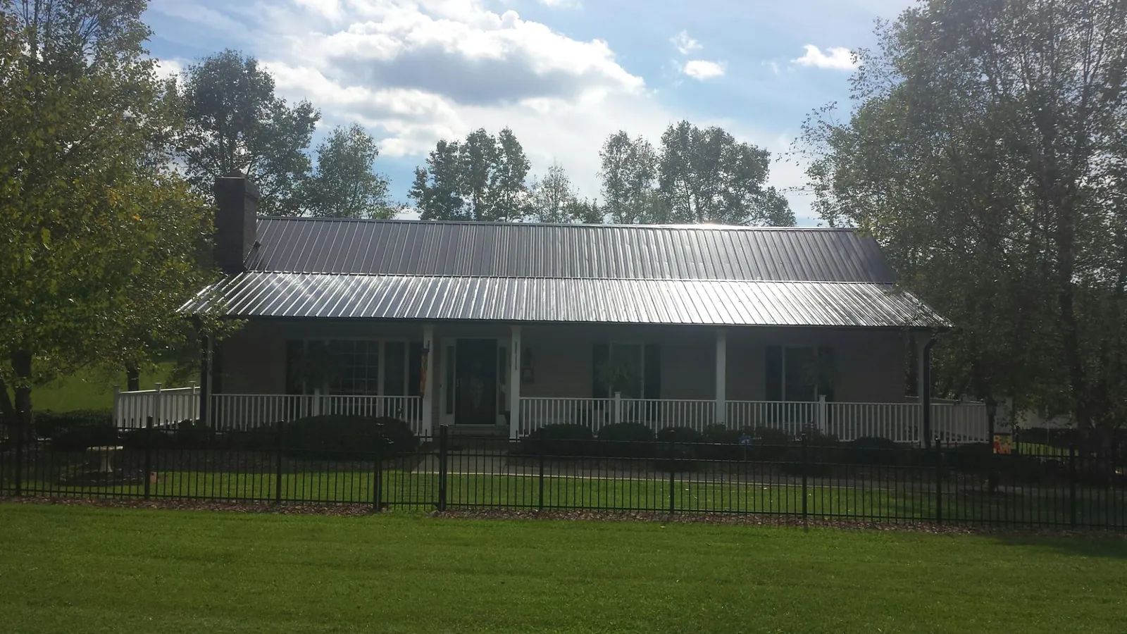 Gray metal roof on a brick ranch with a full width front porch — Gutter Guard Installation work by our crew in Staplehurst