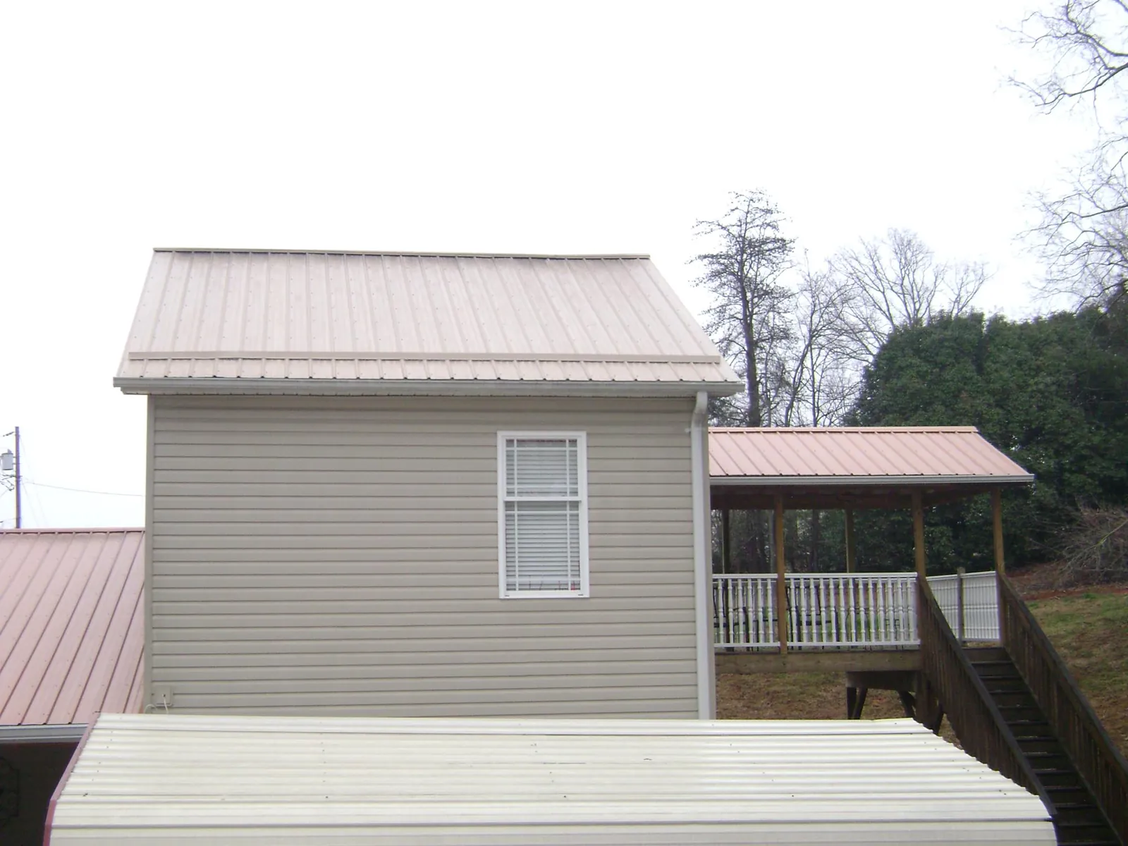 Tan metal roofs on a two story addition and attached porch, from a Roof Replacement job in Staplehurst